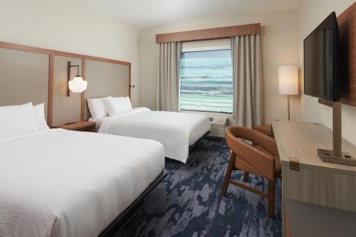 a hotel room with two beds and a desk and a television at Fairfield by Marriott Inn & Suites West Palm Beach in West Palm Beach