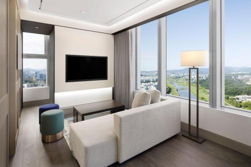 a living room with a white couch and a large window at Hotel Onoma Daejeon, Autograph Collection in Daejeon
