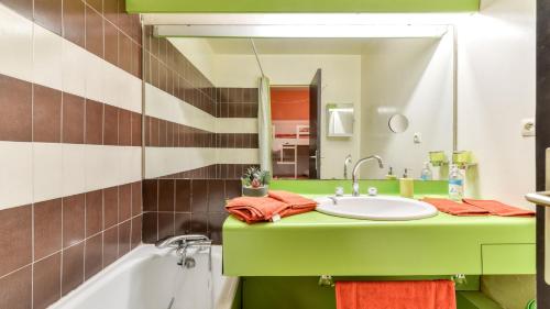 uma casa de banho com um lavatório verde e um espelho em Les Indes Galantes- 72 - Studio vue mer - 6 pers em Cap d'Agde