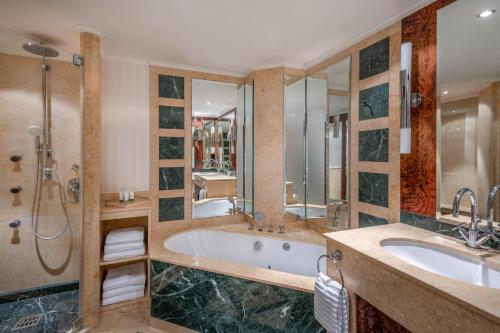 uma casa de banho com uma banheira, um lavatório e um chuveiro em The Westin Grand Munich em Munique