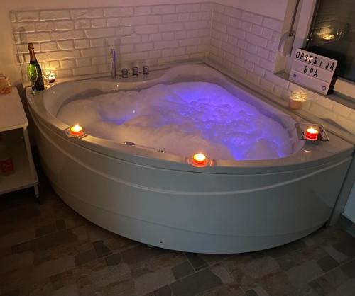 a bath tub filled with blue water with lights in it at Opsesija SPA in Kragujevac
