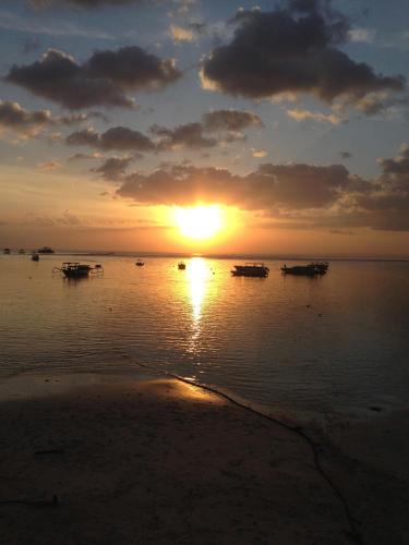 a sunset on the beach with boats in the water at Nusa Indah Bungalow in Nusa Lembongan