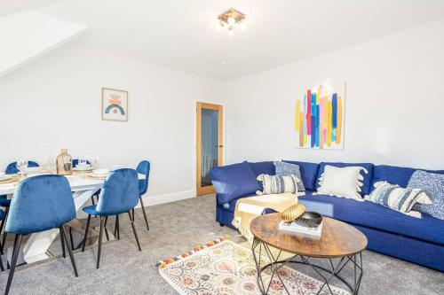 a living room with a blue couch and a table at Beautiful newly refurbished apartment close to the promenade. in Llandudno