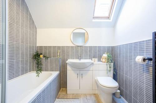 a bathroom with a tub and a toilet and a sink at Beautiful newly refurbished apartment close to the promenade. in Llandudno
