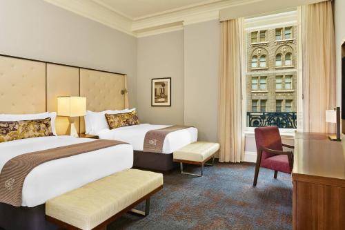 a hotel room with two beds and a desk at Palace Hotel, a Luxury Collection Hotel, San Francisco in San Francisco