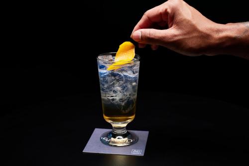 a person holding a lemon in a drink at AC Hotel by Marriott Atlanta Perimeter in Atlanta