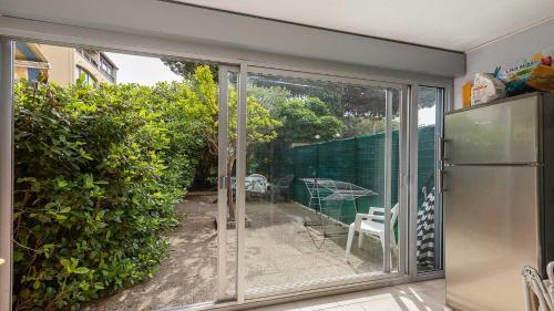 une porte coulissante en verre menant à une terrasse avec une table et des chaises. dans l'établissement Pre St Martin- 3B- Studio loggia vitree- 4 pers, au Cap d'Agde