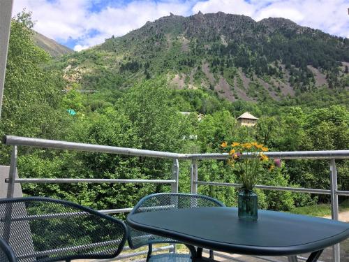 a table with a vase of flowers sitting on a balcony at Hôtel Le Cassini in Le Freney-dʼOisans