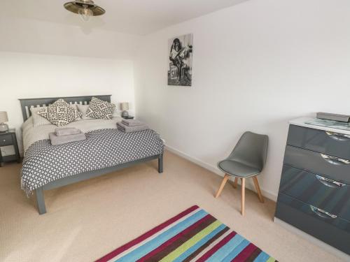 a bedroom with a bed and a chair and a dresser at Sandtop in Tenby