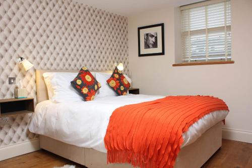 a bedroom with a bed with an orange blanket at Bath View Apartments in Bath