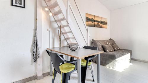 une petite table et des chaises dans une pièce avec un escalier dans l'établissement Les 4 Soleils- 16AB- Studio moderne- 4pers, au Cap d'Agde