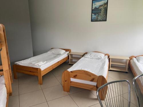 a room with two beds and a chair in it at Żółta Walizka Gościniec in Podrzewie