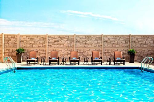 uma piscina com cadeiras e mesas ao lado de uma parede de tijolos em The Westin Galleria Houston em Houston