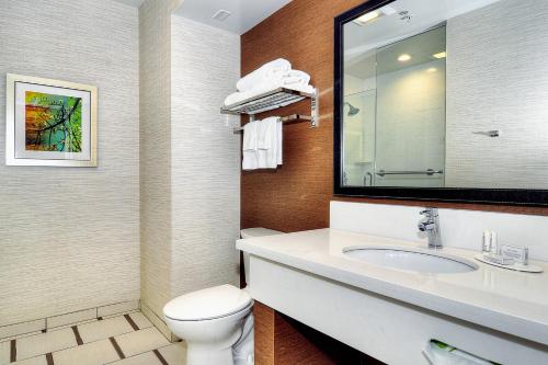 a bathroom with a toilet and a sink with a mirror at Fairfield Inn & Suites by Marriott Los Angeles Rosemead in Rosemead