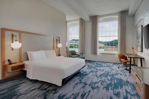 マディソンにあるFairfield Inn & Suites Madison Historic Eagle Cotton Millのベッドとデスクが備わるホテルルームです。