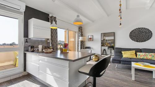 - une cuisine et un salon avec un comptoir et un canapé dans l'établissement Neptuna- 217L- Appart charme- 6 pers, au Cap d'Agde