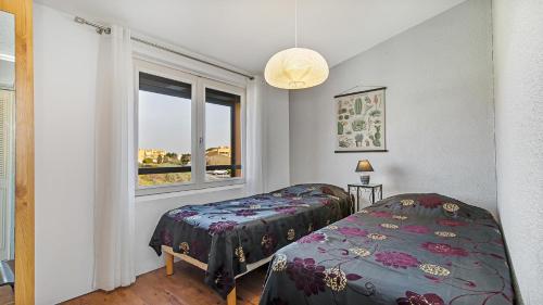 une chambre avec deux lits et une fenêtre dans l'établissement Neptuna- 217L- Appart charme- 6 pers, au Cap d'Agde