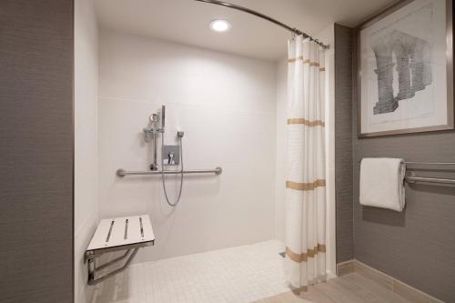a bathroom with a shower with a bench and a shower curtain at Marriott Riverside at the Convention Center in Riverside