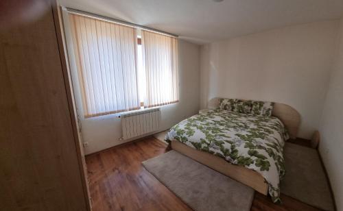 a small bedroom with a bed and a window at Банско Апартментс in Bansko