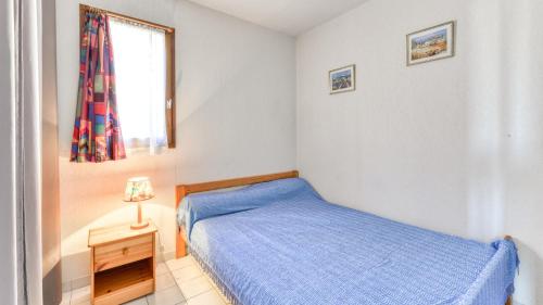a small bedroom with a blue bed and a window at Archipel- 5B- Appart loggia - 4 pers in Cap d'Agde