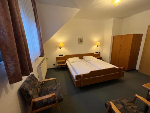 a bedroom with a bed and two chairs in it at Hotel Wolfsjäger in Herbern