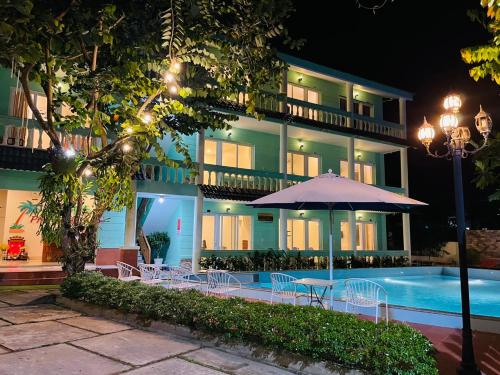 ein Hotel mit einem Pool und einem Tisch mit einem Sonnenschirm in der Unterkunft Phu Long Resort & Bar Phu Quoc in Phu Quoc