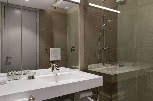 y baño con lavabo blanco y ducha. en AC Hotel by Marriott Cape Town Waterfront, en Ciudad del Cabo
