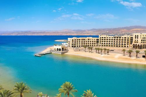 a large body of water with buildings and palm trees at Al Manara, a Luxury Collection Hotel, Aqaba in Aqaba