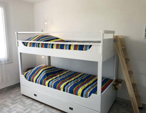 two bunk beds in a room with a ladder at Neptuna- 52B- Appart spacieux- 7 pers in Cap d'Agde