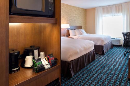 a hotel room with two beds and a television at Fairfield Inn & Suites by Marriott Orlando East/UCF Area in Orlando