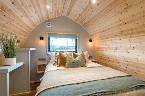 Cama grande en habitación con techo de madera en Country Glamping, en Bishop Auckland