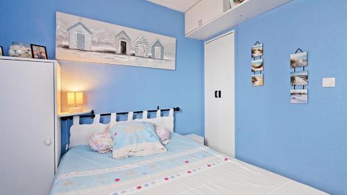 1 dormitorio con paredes azules y 1 cama con almohadas en Port Lano- 109- Appart lumineux- 4 pers, en Cap d'Agde