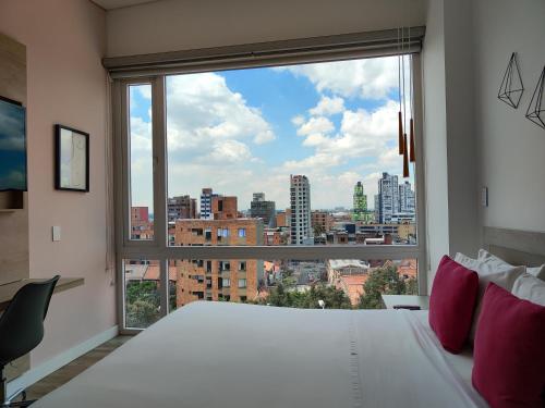 a bedroom with a large white bed and a large window at Urban Heights Bogota in Bogotá