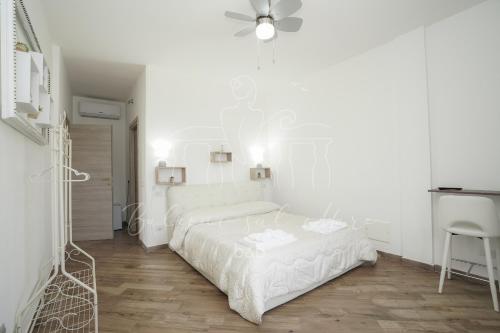 a white bedroom with a bed and a ceiling fan at Balconi sul mare in Otranto