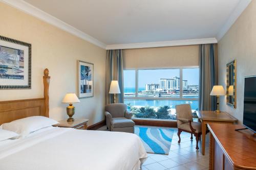 a hotel room with a bed and a desk and a window at Sheraton Jumeirah Beach Resort in Dubai