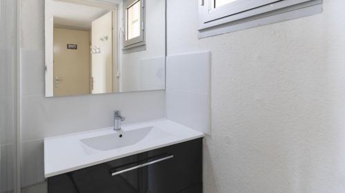 uma casa de banho com um lavatório branco e um espelho. em Aquaplage- 105B- Studio vue mer- 5 pers em Cap d'Agde