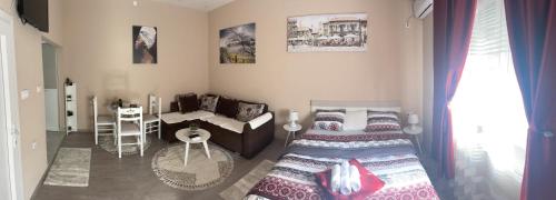 a bedroom with two beds and a table and a couch at Apartment Downtown in Podgorica