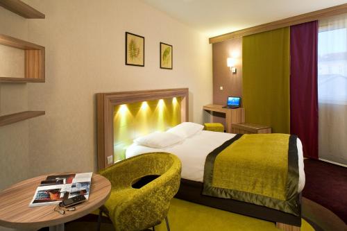 リブルヌにあるメルキュール リブルヌ サン テミリオンのベッドとテーブルが備わるホテルルームです。