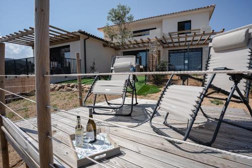 una terraza con 2 sillas y 2 botellas de vino en Di Luce, en Lumio