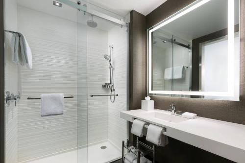 uma casa de banho com um chuveiro, um lavatório e um espelho. em AC Hotel Park City em Park City