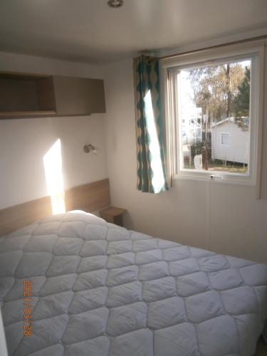 Un dormitorio con una gran cama blanca y una ventana en Mobilhome 3 chambres tout confort, proche de la plage en Saint-Brevin-les-Pins