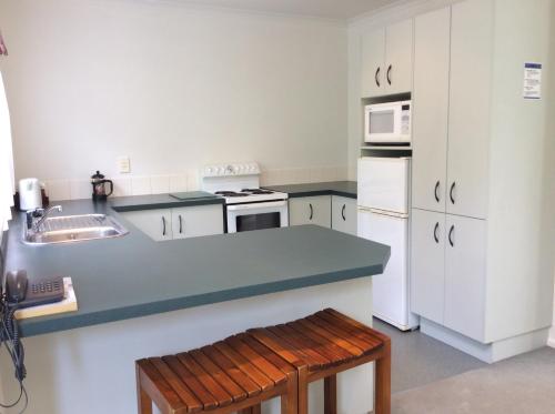 a kitchen with white appliances and a blue counter top at Camelot Motor Lodge and Conference Centre in Palmerston North