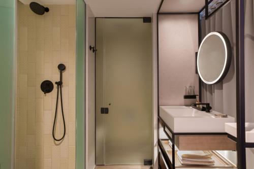 a bathroom with a shower and a sink and a mirror at Renaissance New York Flushing Hotel at Tangram in Queens