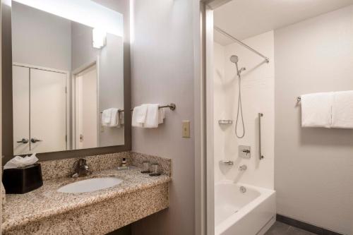 a bathroom with a sink and a tub and a mirror at Courtyard Denver Southwest/Lakewood in Lakewood