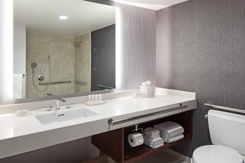 a bathroom with a sink and a mirror and a toilet at San Mateo Marriott San Francisco Airport in San Mateo