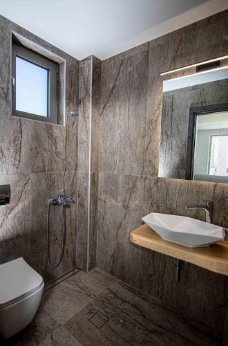 a bathroom with a sink and a toilet and a mirror at Crete Villa Paseathea, Luxurious Pool Getaway in Kamilari