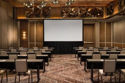 an empty room with tables and chairs and a projection screen at AC Hotel by Marriott Austin-University in Austin