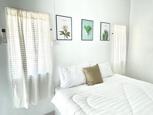 Dormitorio blanco con cama y cuadros en la pared en Seamsak hotel en Golden Triangle