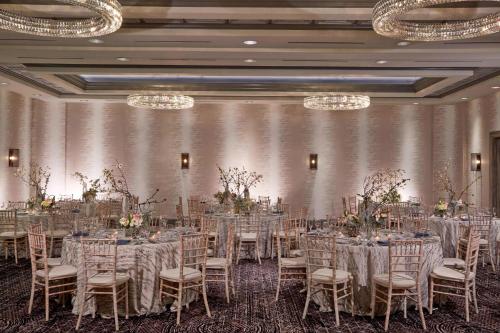 a banquet room with tables and chairs and chandeliers at Rochester Airport Marriott in Rochester