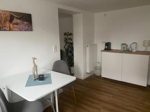 a living room with a white table and a kitchen at Klein aber oho! Neues Apartment in Stadt- und Fuldanähe in Kassel